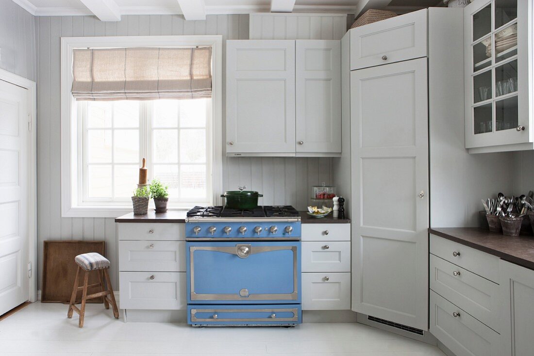 weiße, skandinavische Landhausküche mit hellblauem Gasherd und nostalgischem Flair