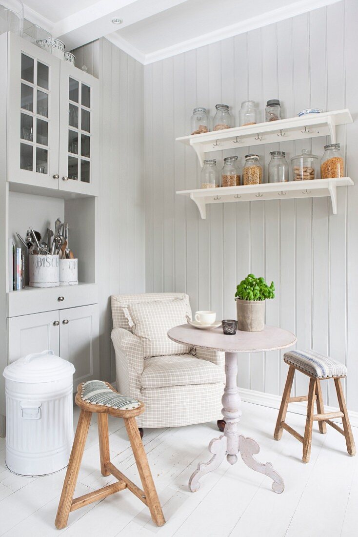 Armchair, table and wooden stools in corner of Scandinavian country-house kitchen
