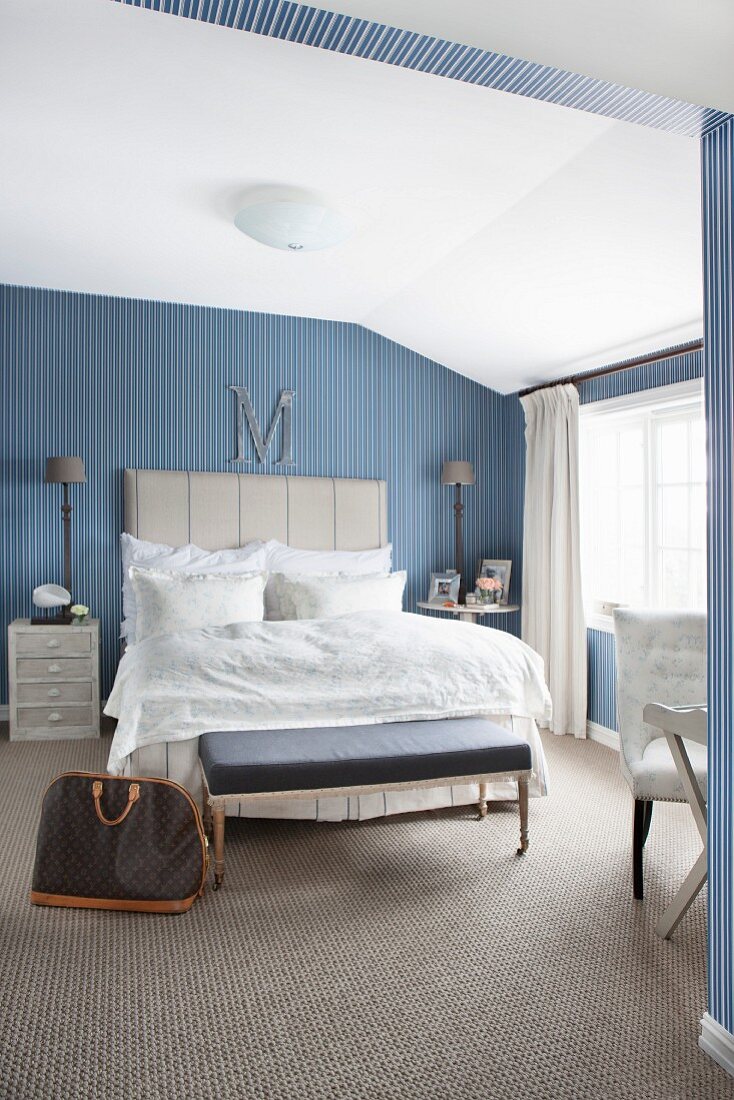 Elegantes Schlafzimmer mit blau-weißer Streifentapete und nostalgischem Flair