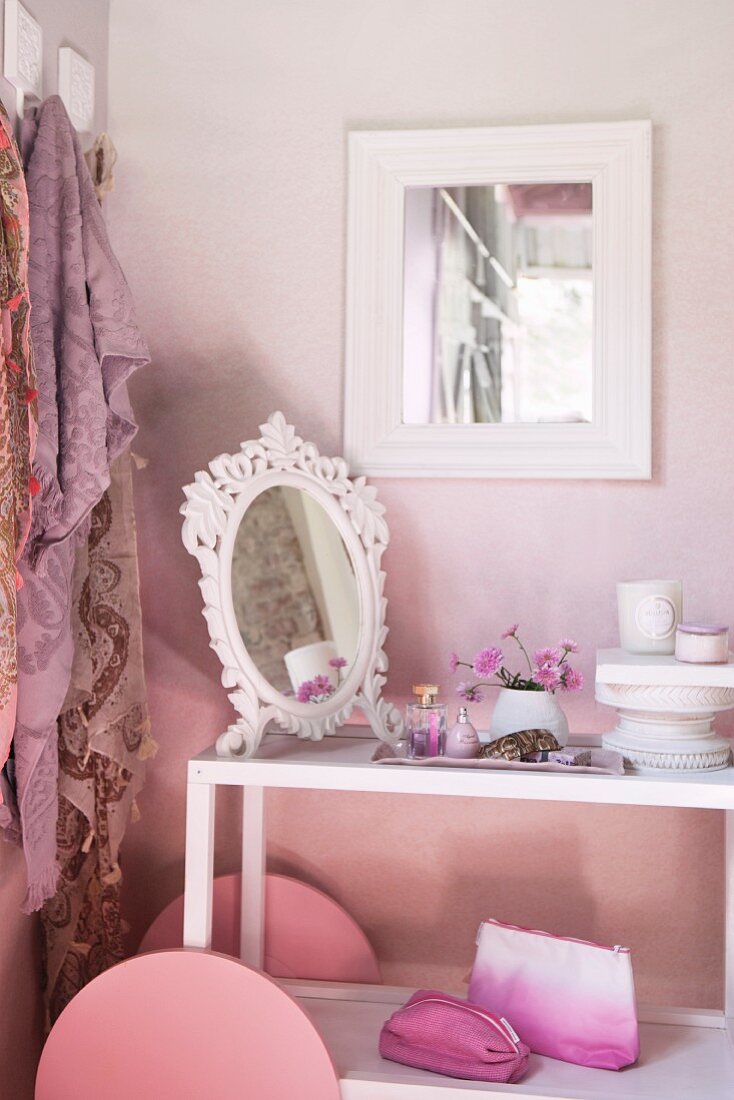 Servierwagen als Schmintktisch mit Spiegel und Kosmetikzubehör vor rosa getönter Wand