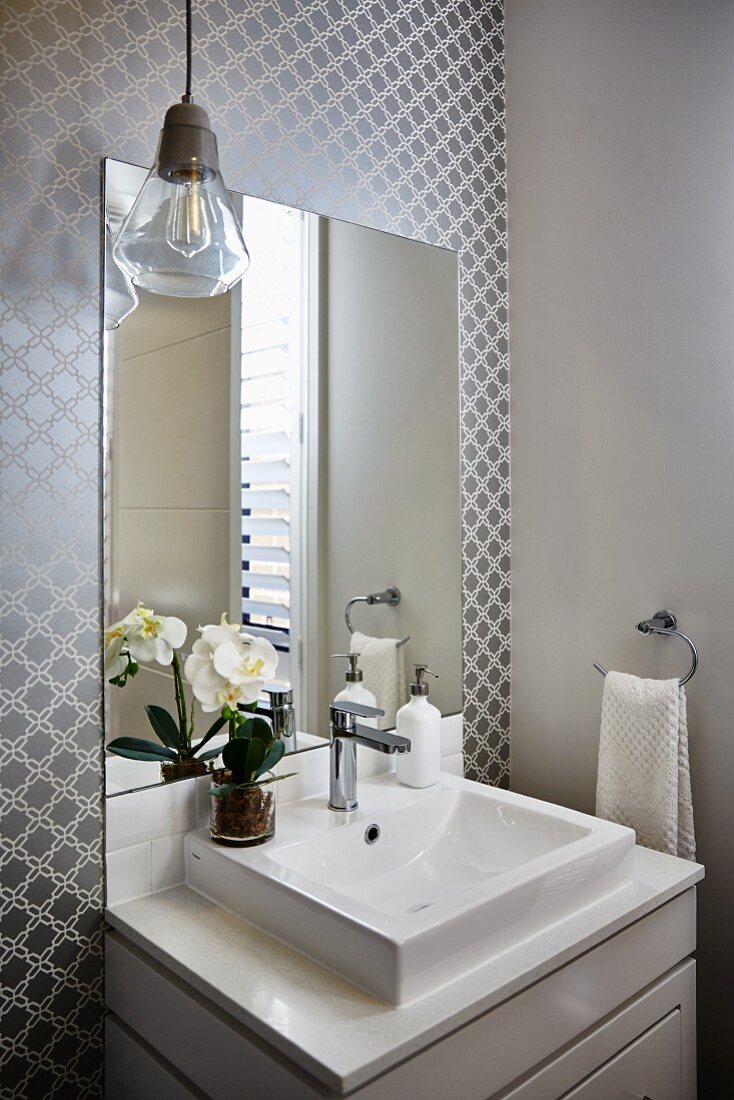 Waschtisch mit Unterschrank vor Spiegel an Wand mit grauem Retro Muster