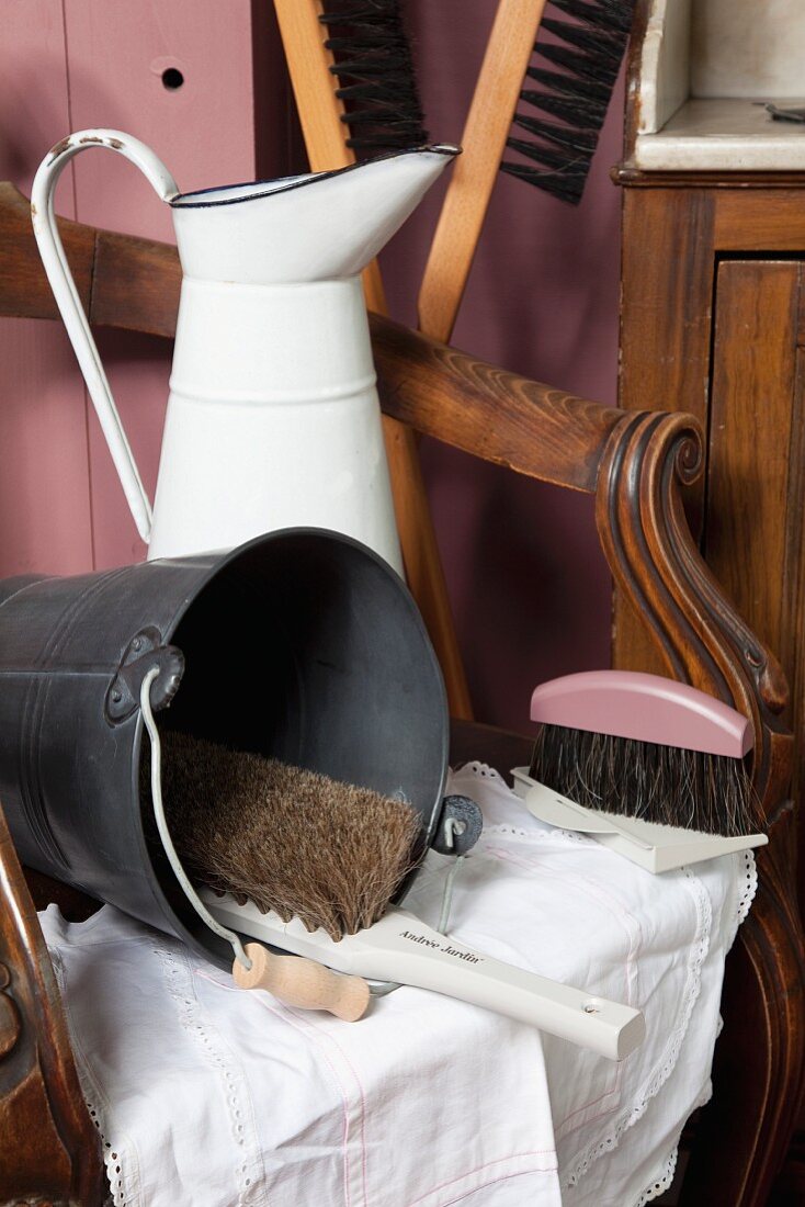 Retro enamel jug, metal buckets and brushes on antique armchair