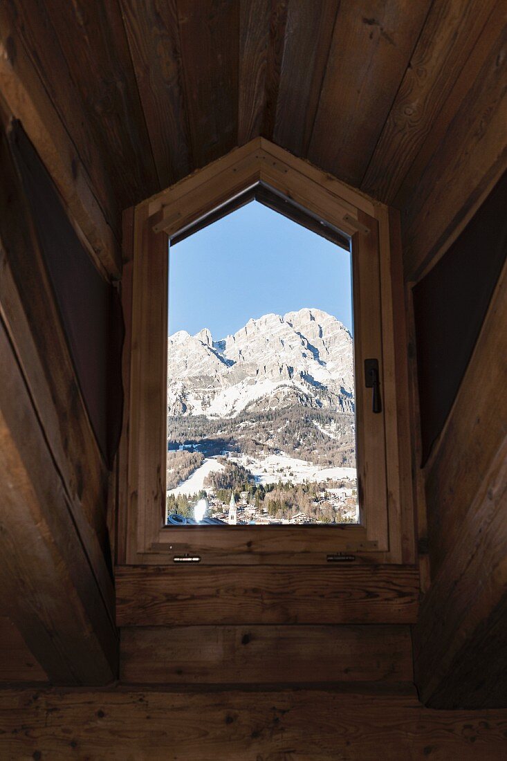 Blick auf die Dolomiten durch rustikales Dachgaubenfenster eines Chalets