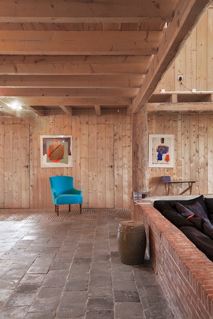 Türkisfarbener Sessel in renoviertem Wohnraum mit Holzverkleidung