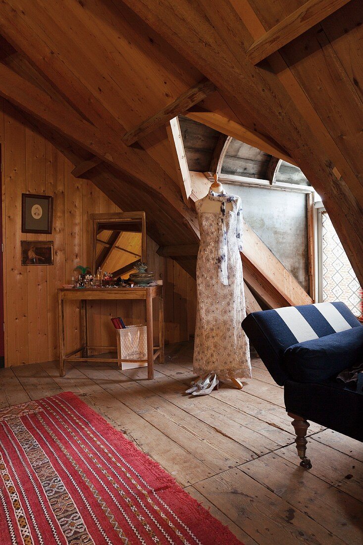 Wood-clad attic room with tailors' dummy wearing long summer dress in dormer
