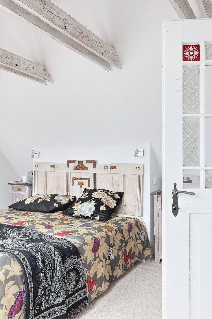 Doppelbett mit floral gemusterter Tagesdecke und kunsthandwerklichem hölzernem Bettkopfteil in Schlafzimmer