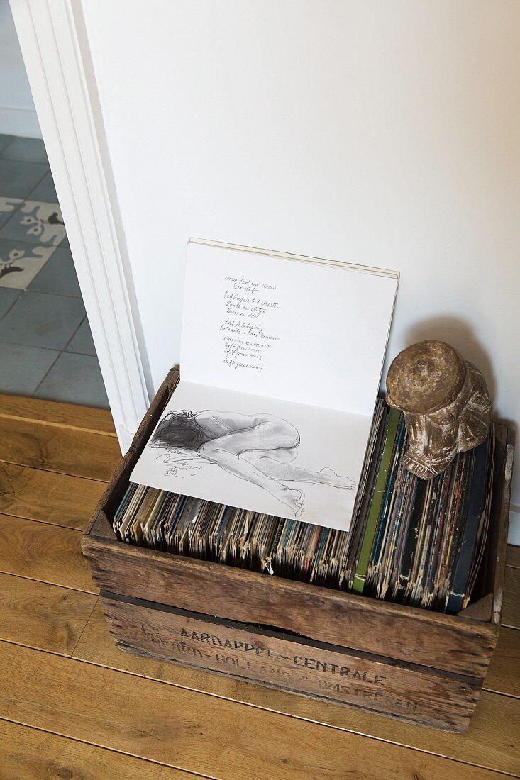 Aufgeschlagenes Buch mit Gedicht und Aktzeichnung auf Schallplattensammlung in alter Holzkiste