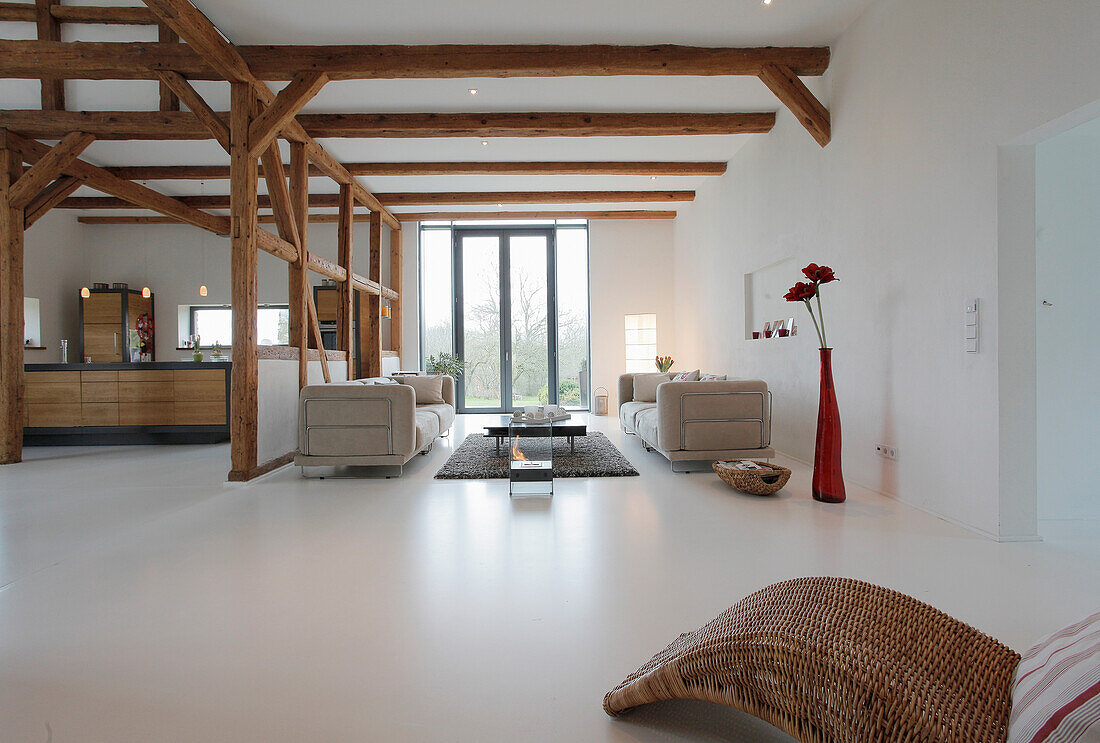 Loftartiges Wohnzimmer mit freiliegenden Holzbalken und Designermöbeln