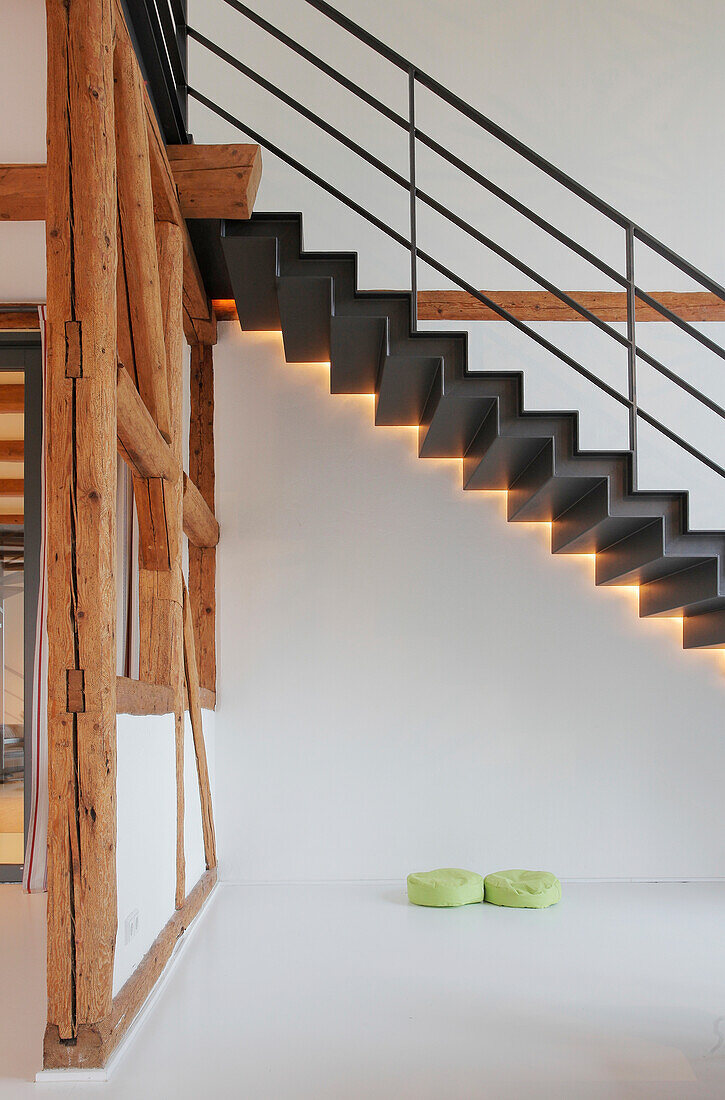 Moderne Treppe mit indirekter Beleuchtung neben rustikalen Holzbalken