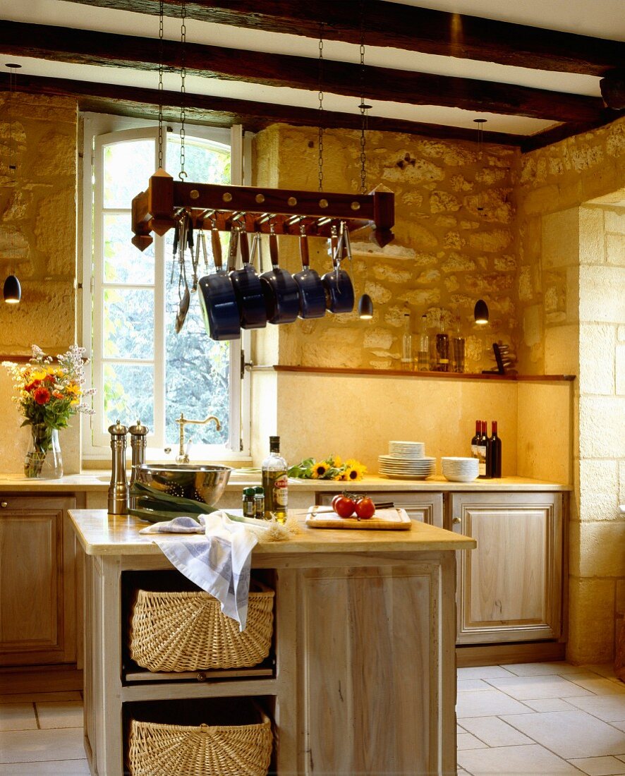 Kücheninsel aus Massivholz mit Schrankelement, unter abgehängte Pfannen, in rustikaler Küche