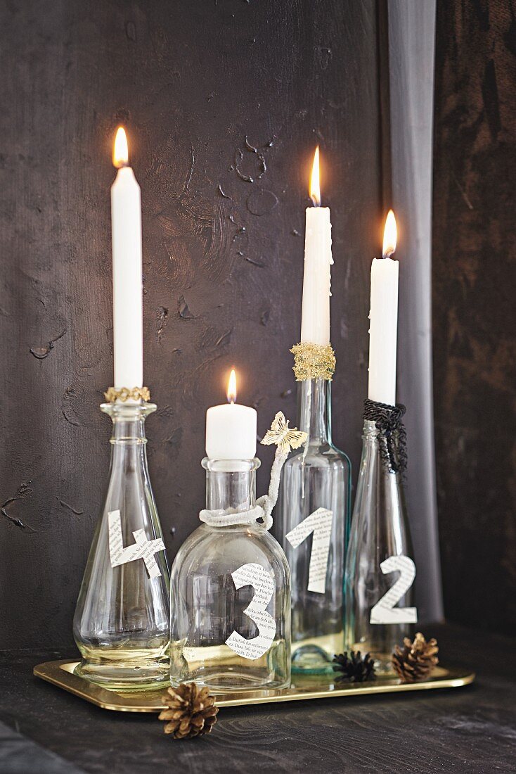 Weihnachtlich dekorierte Glasflaschen mit Kerzen als Adventskranz