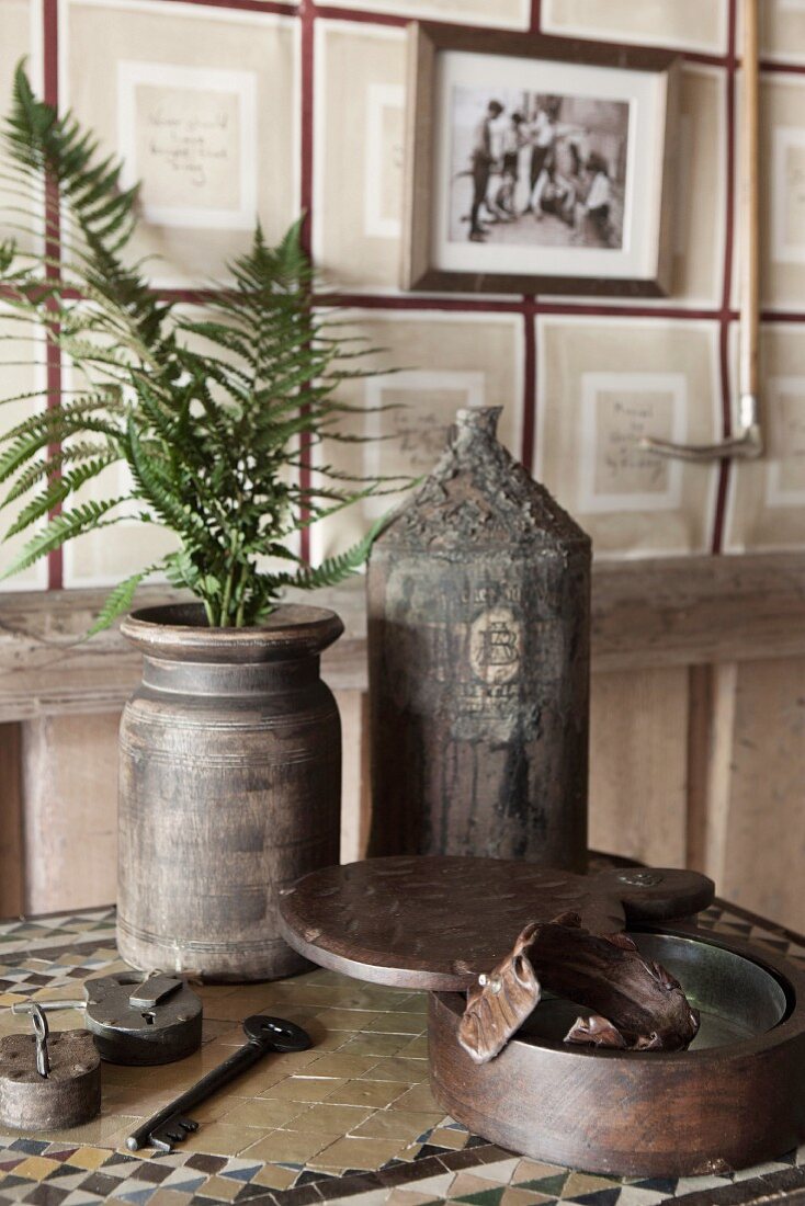 Farnzweige in Vintage Vase und Flasche auf Tisch in rustikalem Ambiente