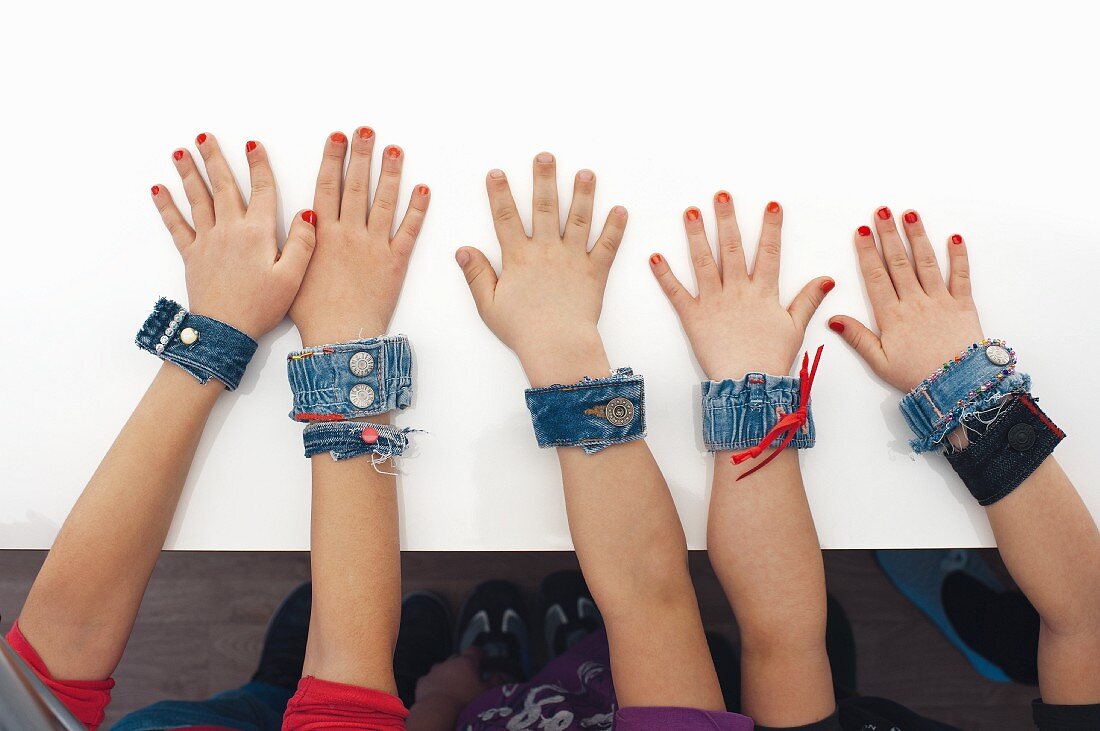 Arms of children wearing denim bracelets