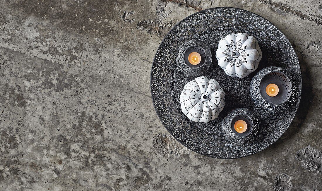 Schwarz-weiss bemalte Kürbisse mit Ornamentmuster und Schälchen mit Teelichtern