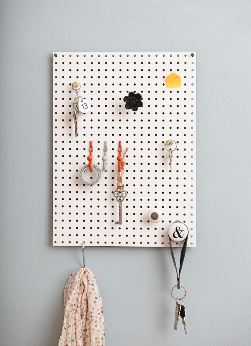 DIY key rack made from white perforated panel and various hooks and knobs