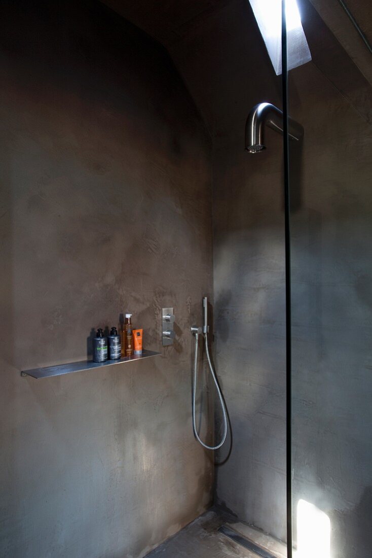 Pattern of light and shade in minimalist shower area with designer tap fittings and grey walls