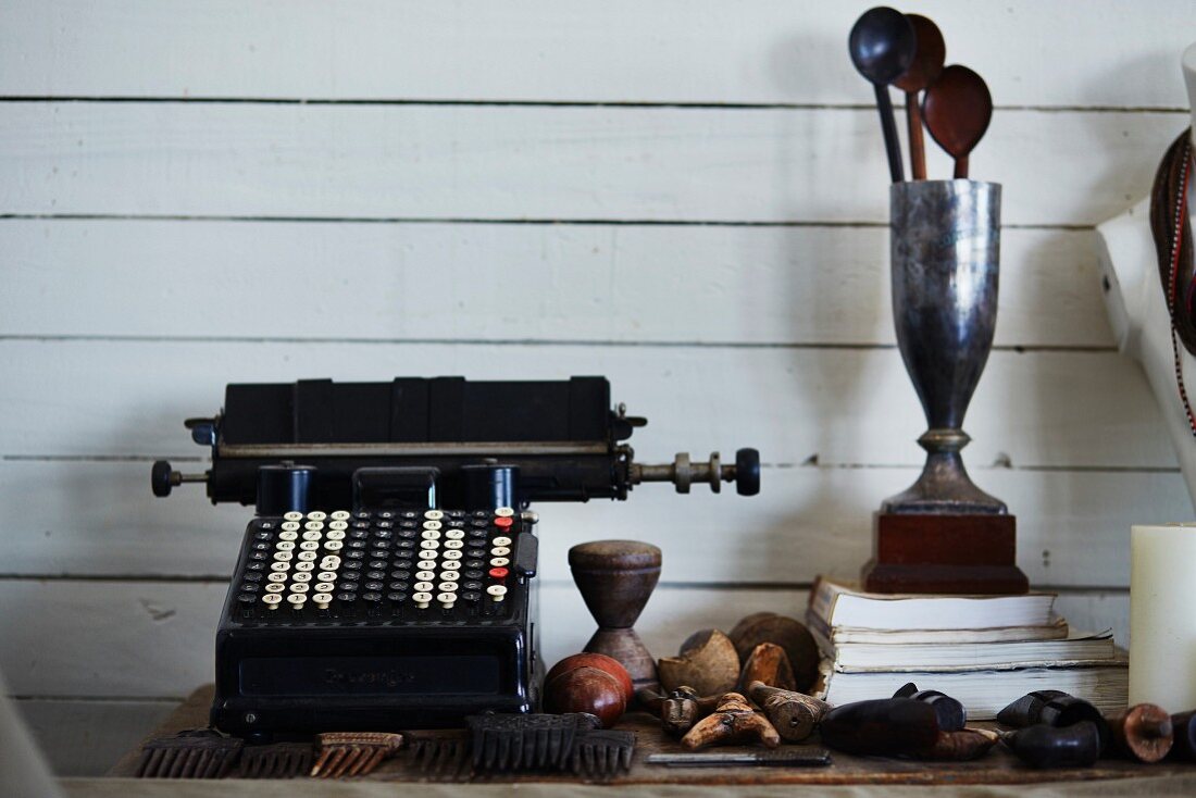 Vintage typewriter and spoons in trophy against white, wood-clad wall