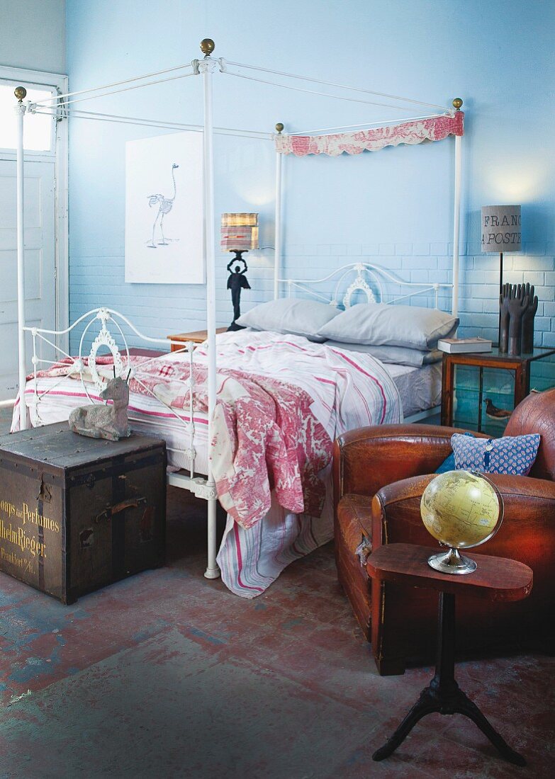 Schlafzimmer mit nostalgischem Metallhimmelbett und antikem Ledersessel