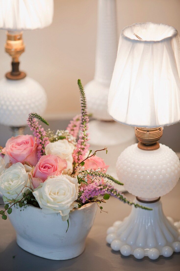 weiße Porzellan-Tischleuchten neben romantischem Rosenstrauss