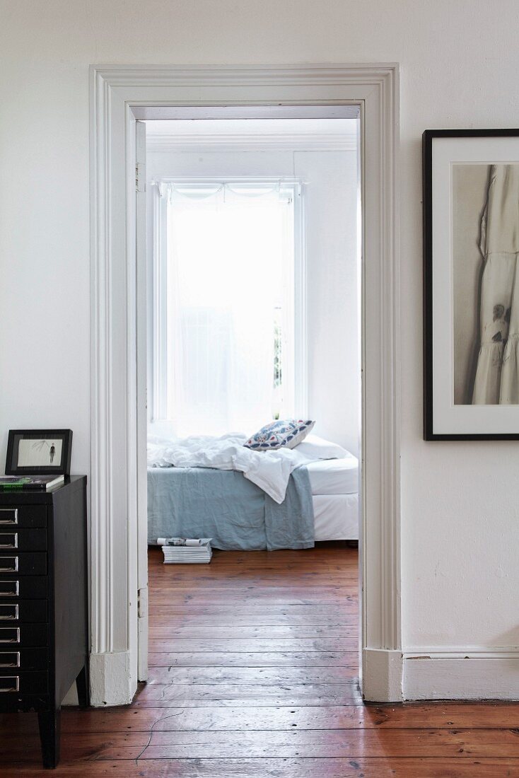 View through open interior door into bedroom with wooden floor