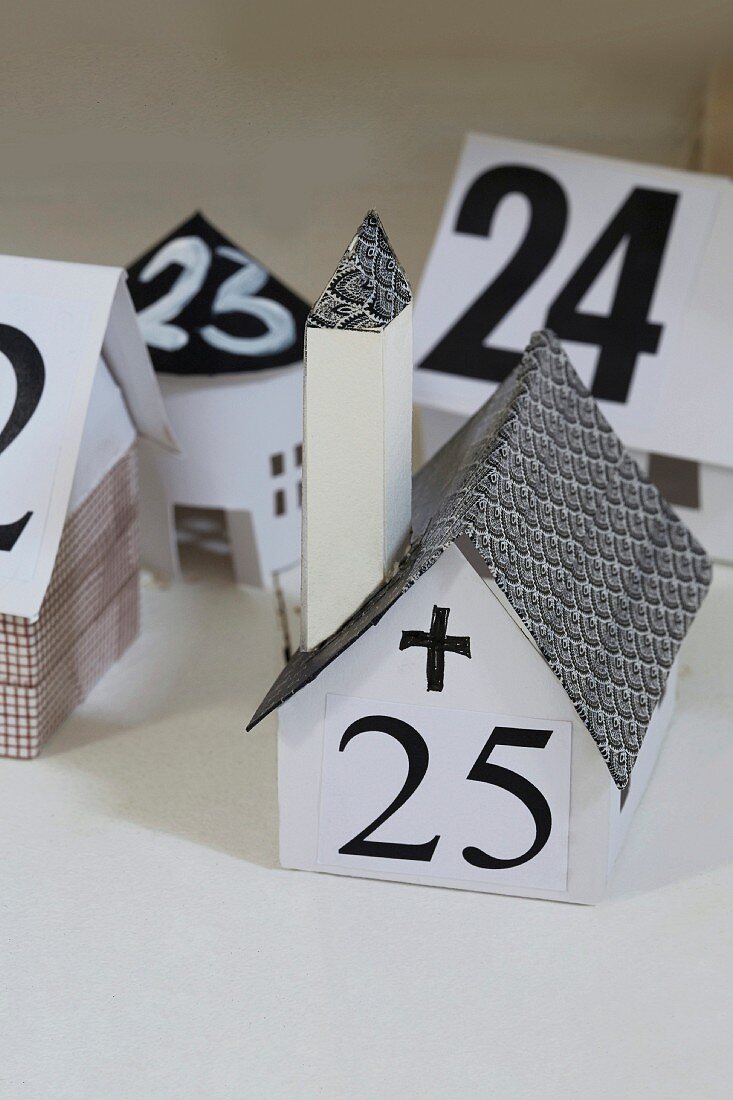Adventskalender aus schwarz-weißen Papierhäuschen gebastelt mit aufgeklebten Zahl