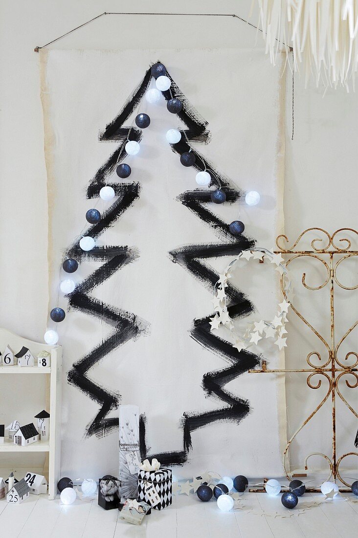 weiße Stoffbahn mit aufgemaltem schwarzem Weihnachtsbaum und Lichterkette an Wand