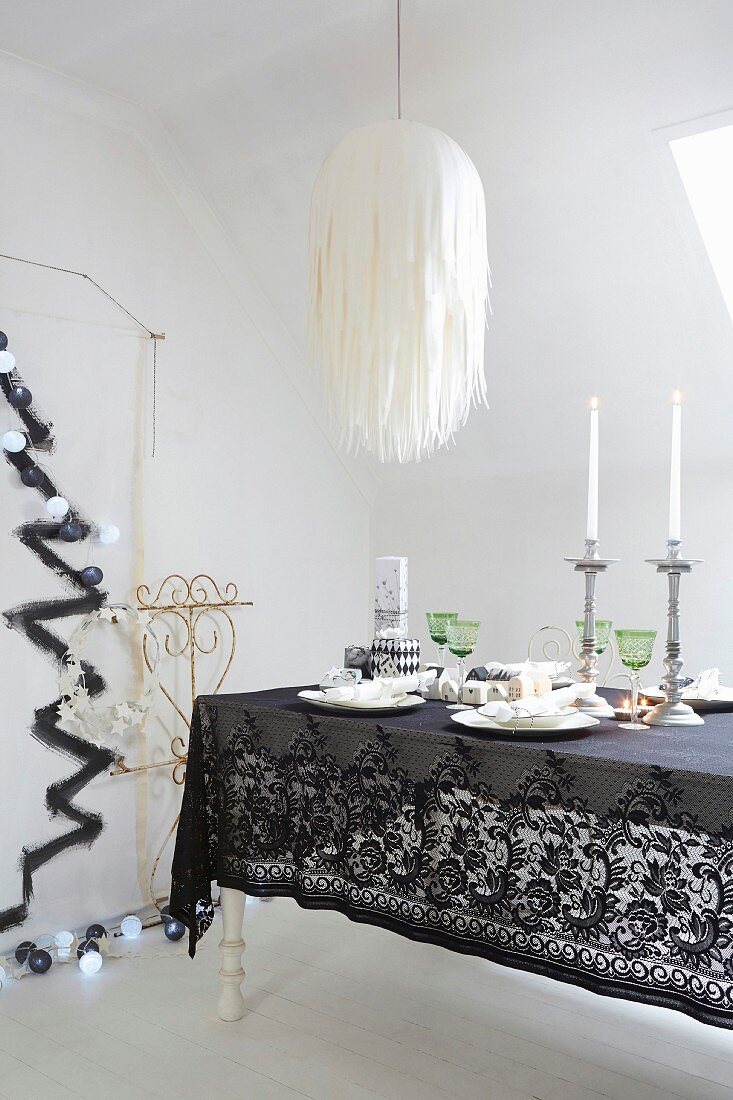 Festively decorated Christmas dining table with black lace tablecloth under paper lampshade