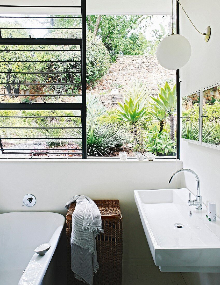 Modernes Waschbecken neben offenem Fenster mit Gartenblick