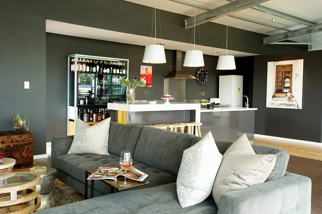 Grey sofa combination and kitchen island in open-plan interior with grey-painted walls