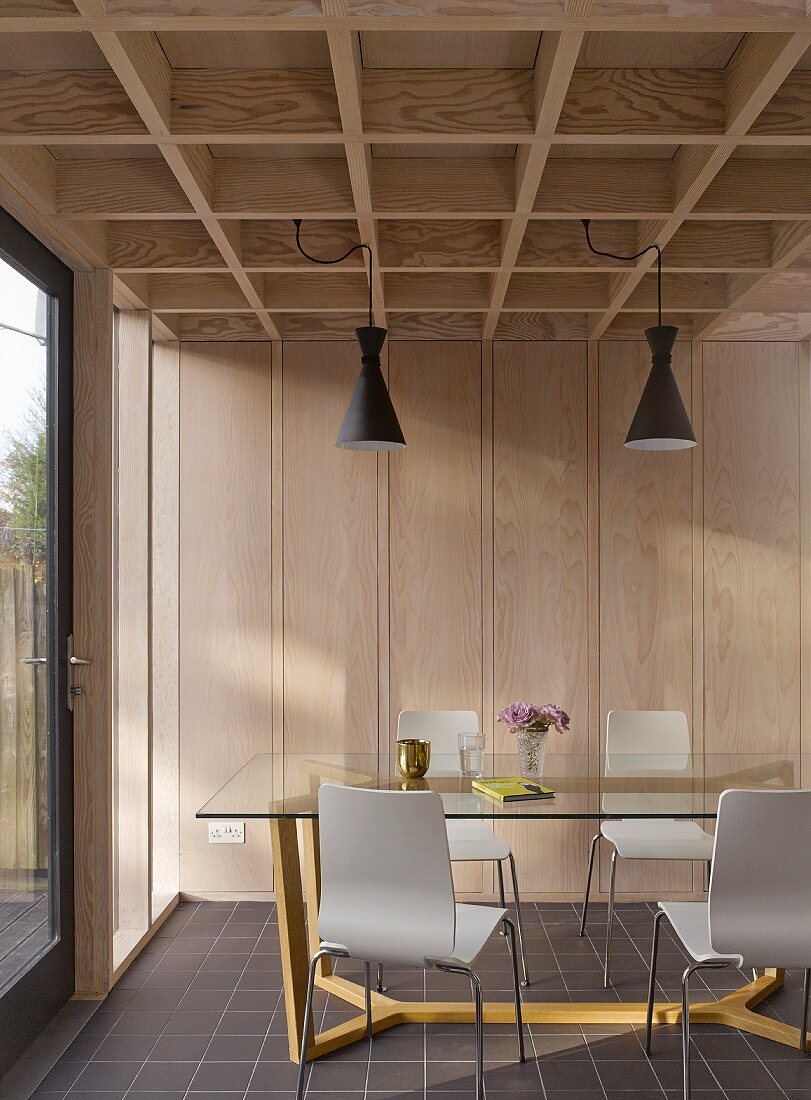 Moderne Holz-Kassettendecke und Pendelleuchten über Designer Essplatz mit Glastisch auf gelbem Metallgestell