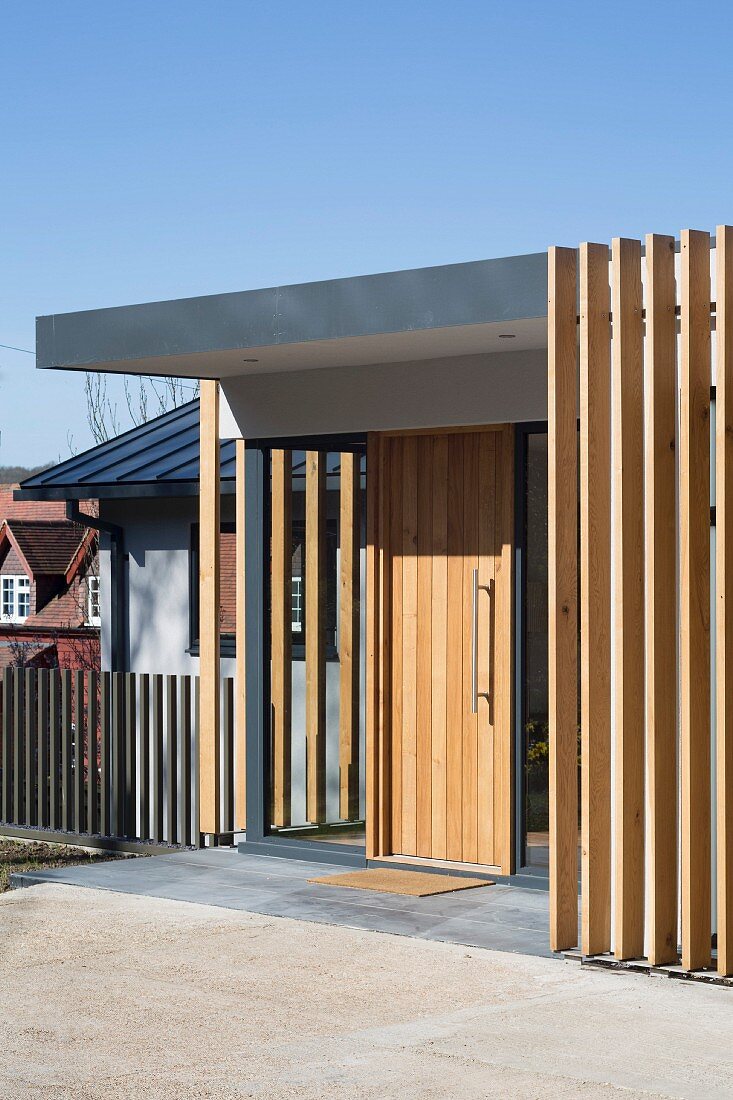 Entrance of contemporary house with simple wooden door and vertical wooden structure to one side