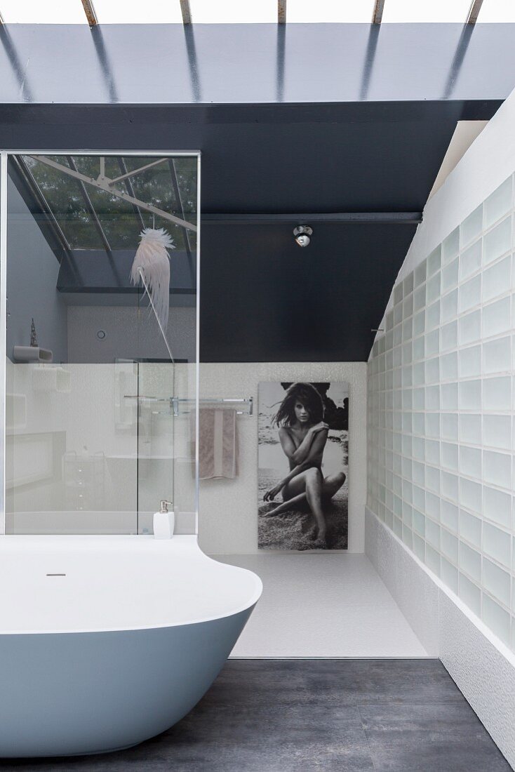 Elegant minimalist bathroom with glass-brick wall and designer bathtub