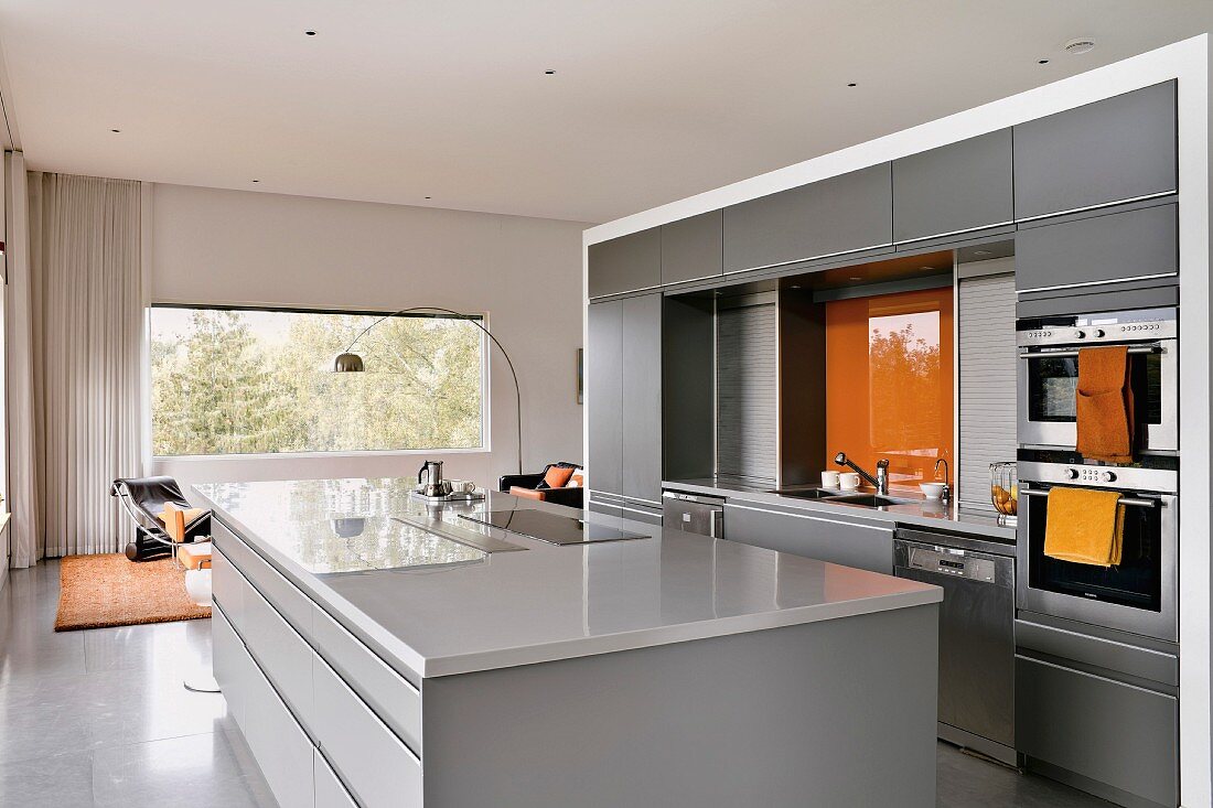 Moderne offene Küche in Hellgrau mit orangefarbenen Farbakzenten