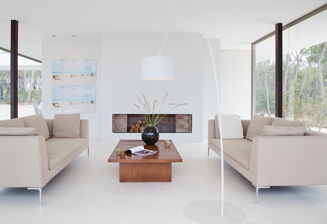 Designer-Loungebereich mit offenem Kamin, weißem Boden und raumhohen Verglasungen