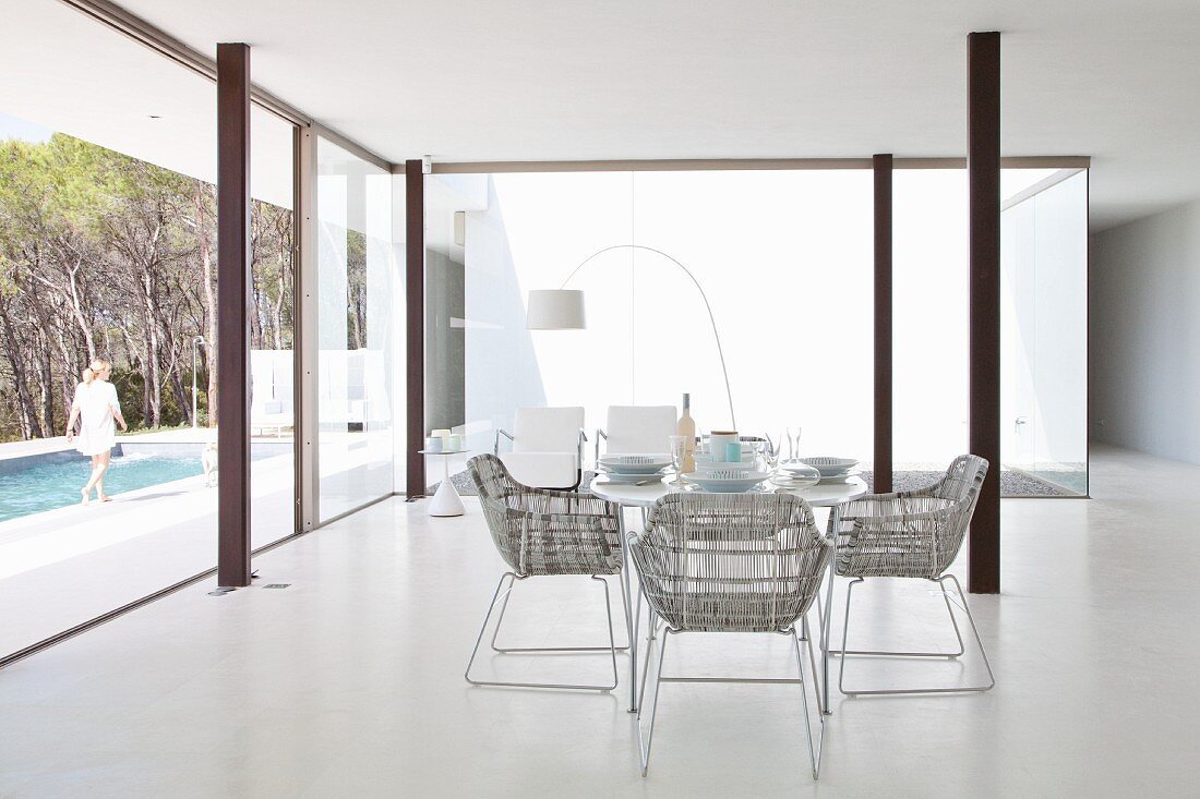Essbereich in minimalistischem Luxusambiente mit Stahlstützen und Blick auf Pool