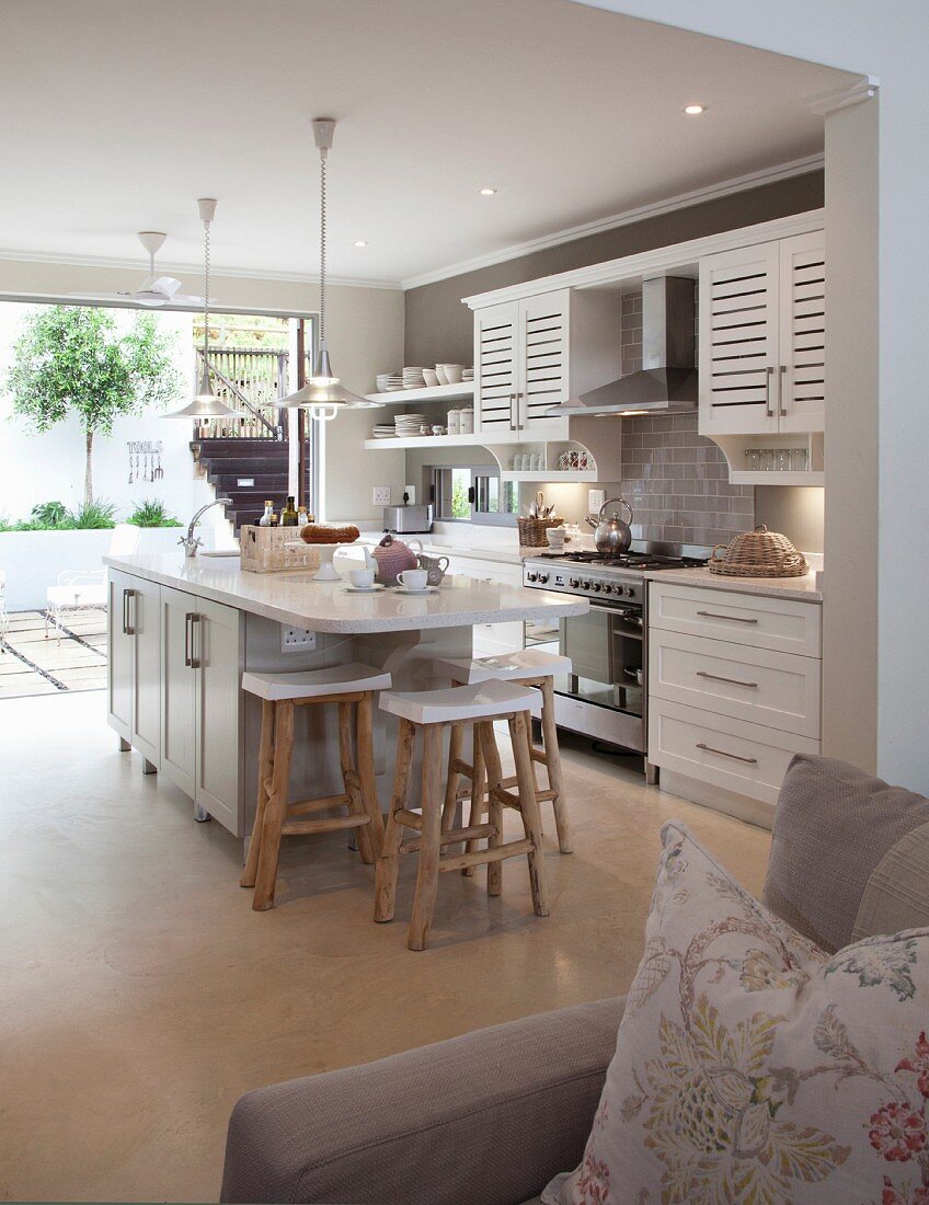 Blick vom Sofa auf die offene Landhausküche mit Frühstückstresen und Barhockern