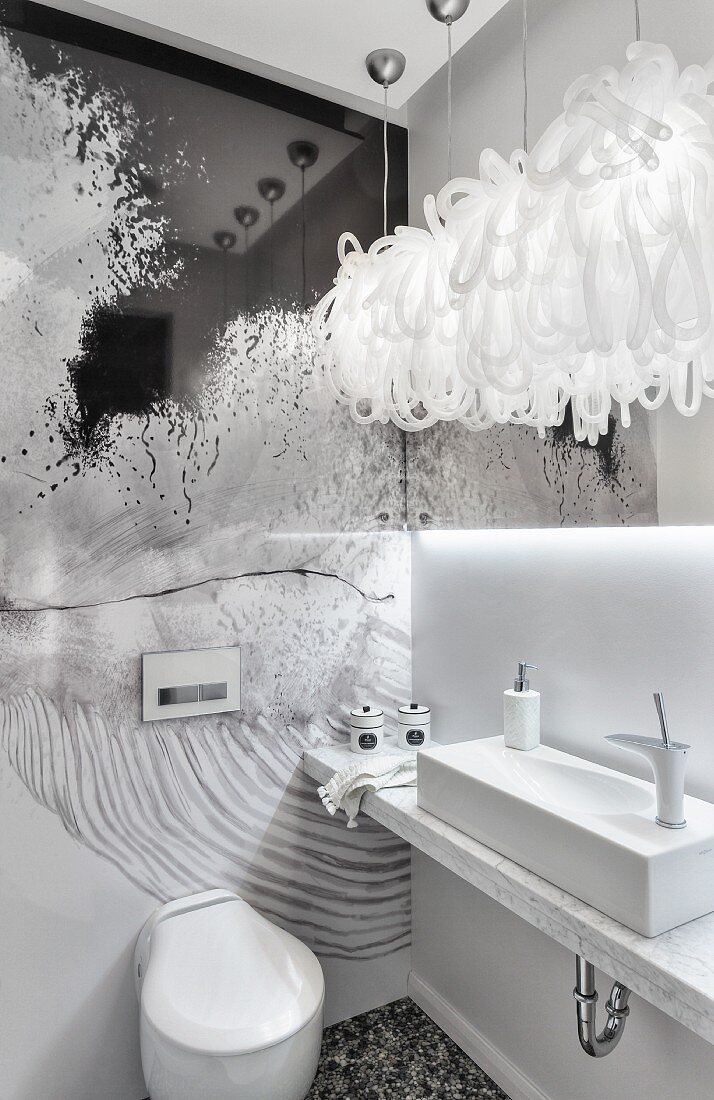Minimalistischer Waschtisch mit Marmorplatte und künstlerische Wandgestaltung in weißem Designerbad