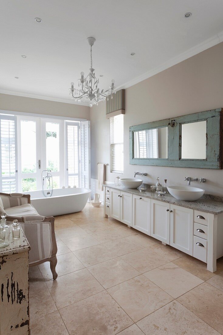 Waschtischzeile mit zwei Aufbaubecken, im Hintergrund freistehende Badewanne vor Fenstertüren, grossformatiger Fliesenboden in grosszügigem Bad