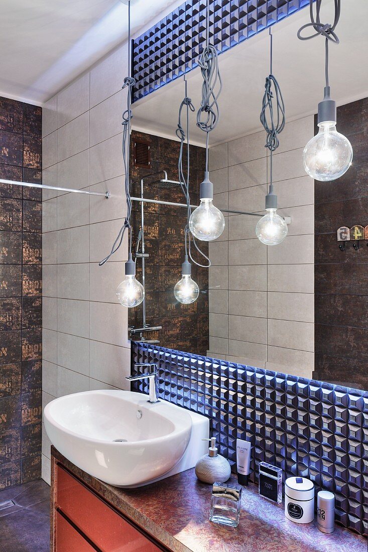 Blau schimmernde, futuristische Strukturwand mit Spiegel hinter Waschtisch, Bulb Pendelleuchten mit Kabelverknotung