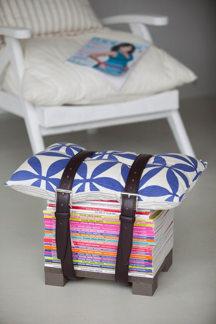 Stool made from stacked magazines and cushion strapped together with belts