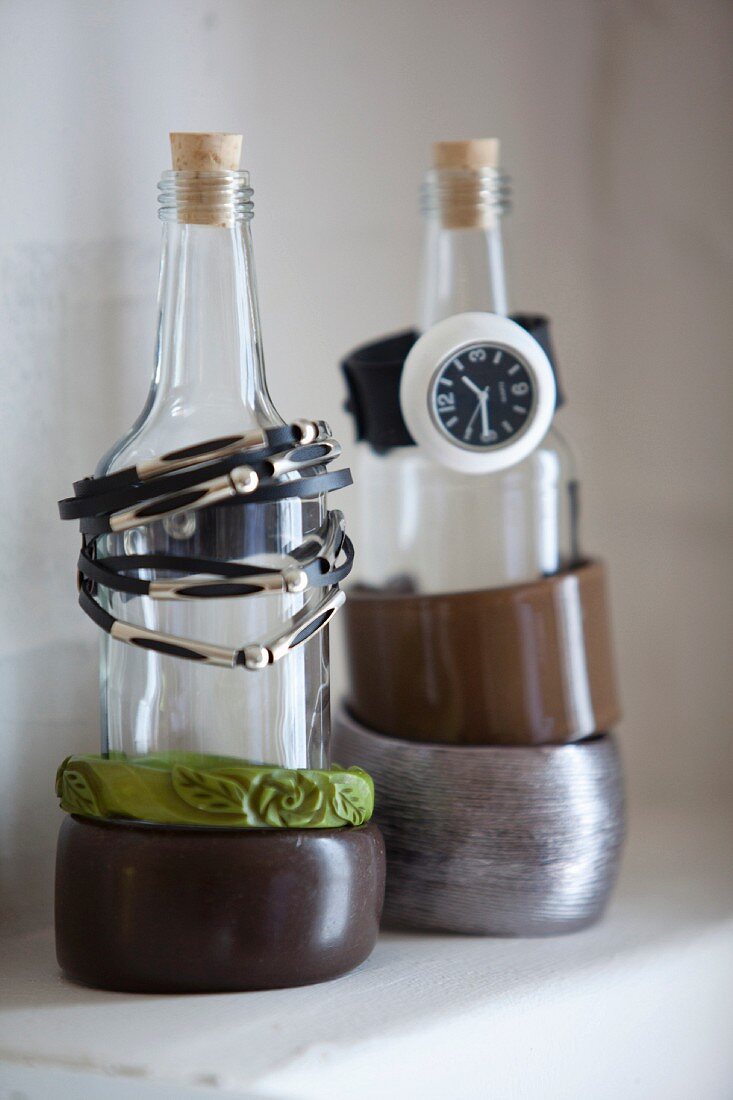 Armbänder und Armbanduhr auf Flaschen, als Schmuckständer