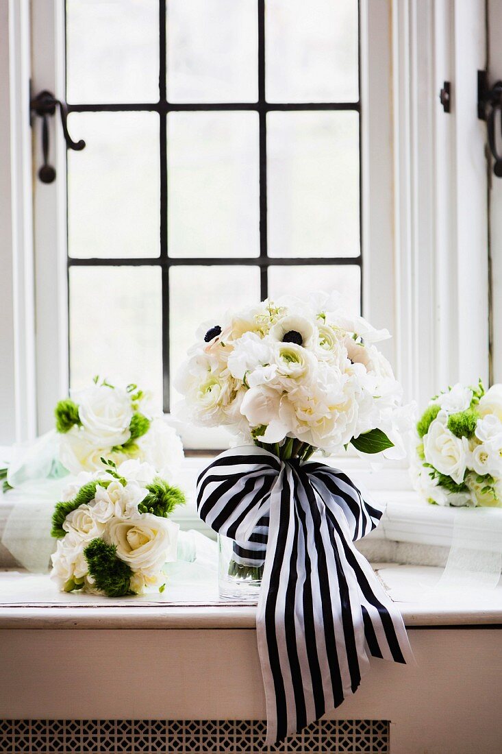Bridal bouquet of white roses with black and white ribbon on windowsill