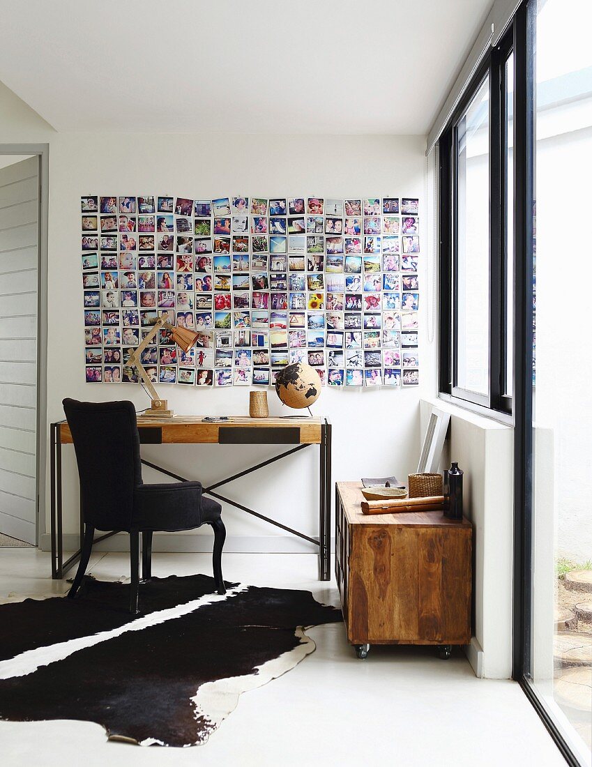Console table and black-upholstered chair below photo collage on wall