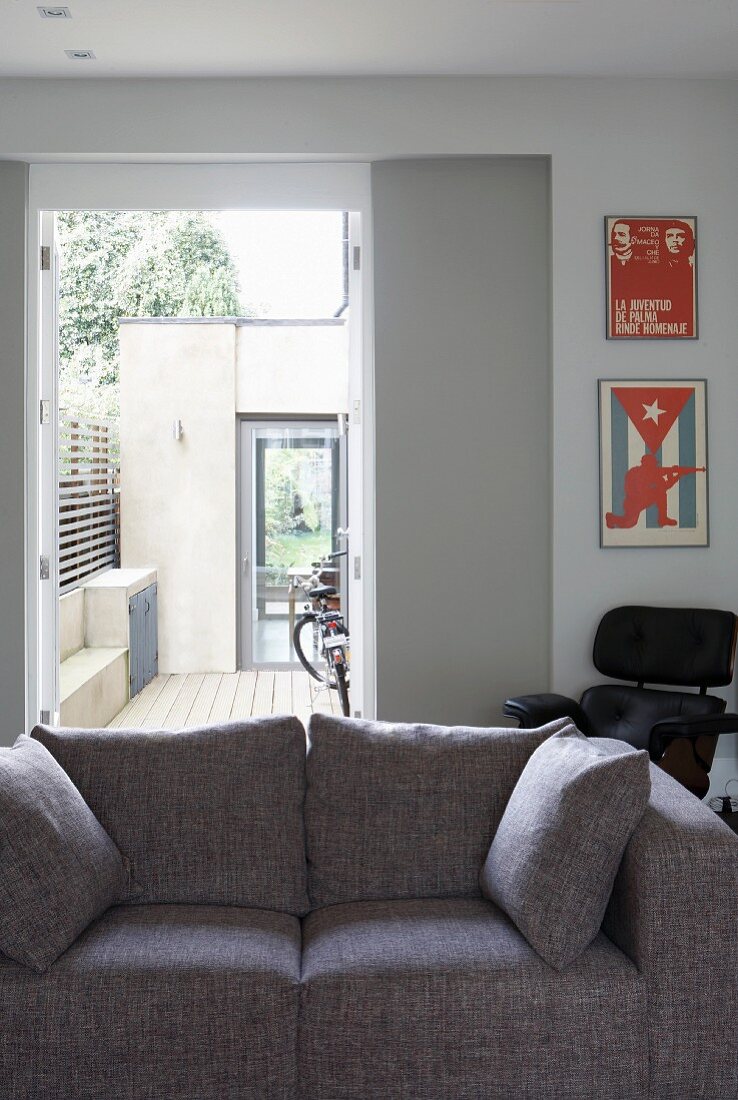 Grey sofa in front of open terrace doors with view of bicycle outside in courtyard