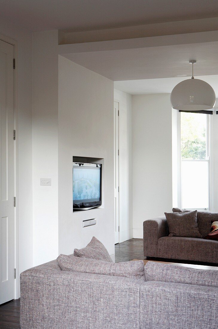 Grey sofas in front of TV in niche