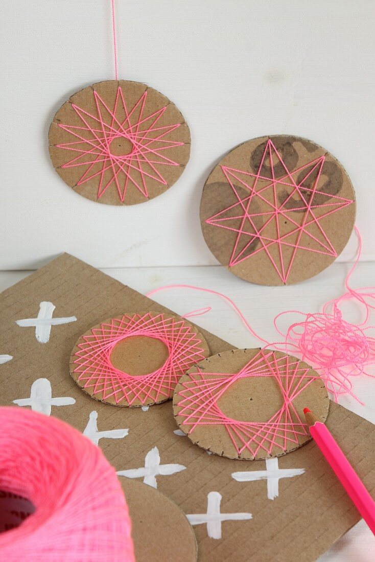 Hand-crafted, circular cardboard decorations with patterns of thread