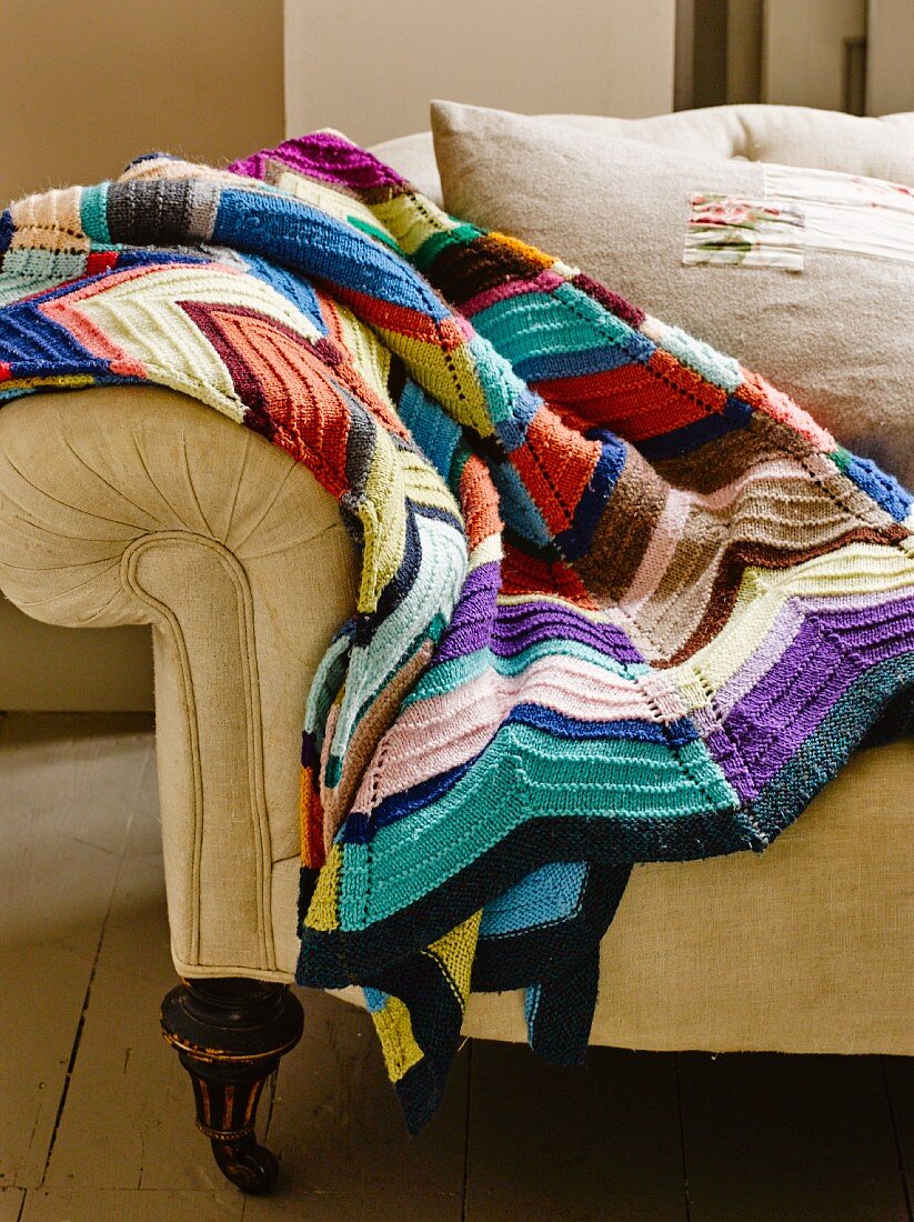 Blanket crocheted from colourful odds and ends of yarn on sofa