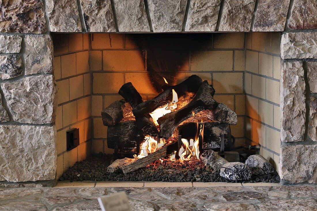 Feuer in rustikalem, offenem Kamin, mit Naturstein Einfassung