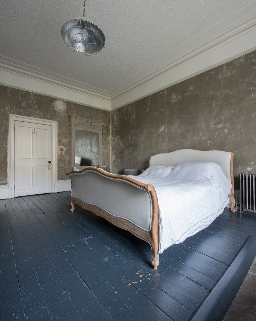 Schlafzimmer mit Schlittenbett auf graublau lackiertem Dielenboden und patinierter Wand