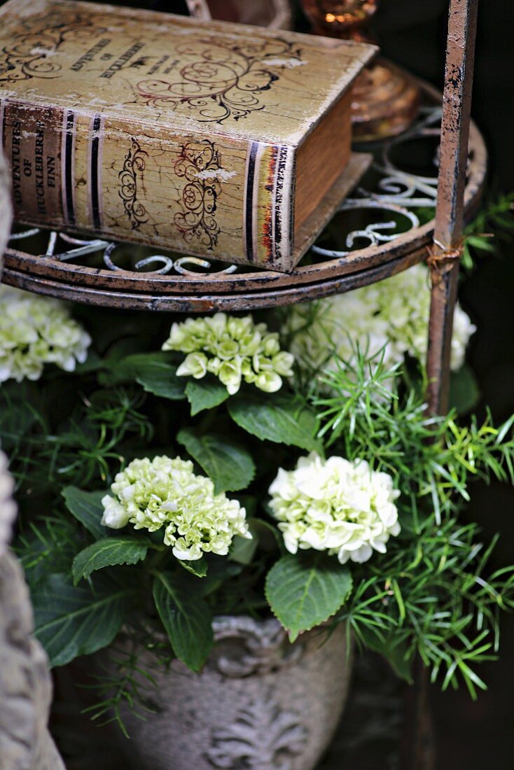 White hydrangea and antique book on metal plant stand